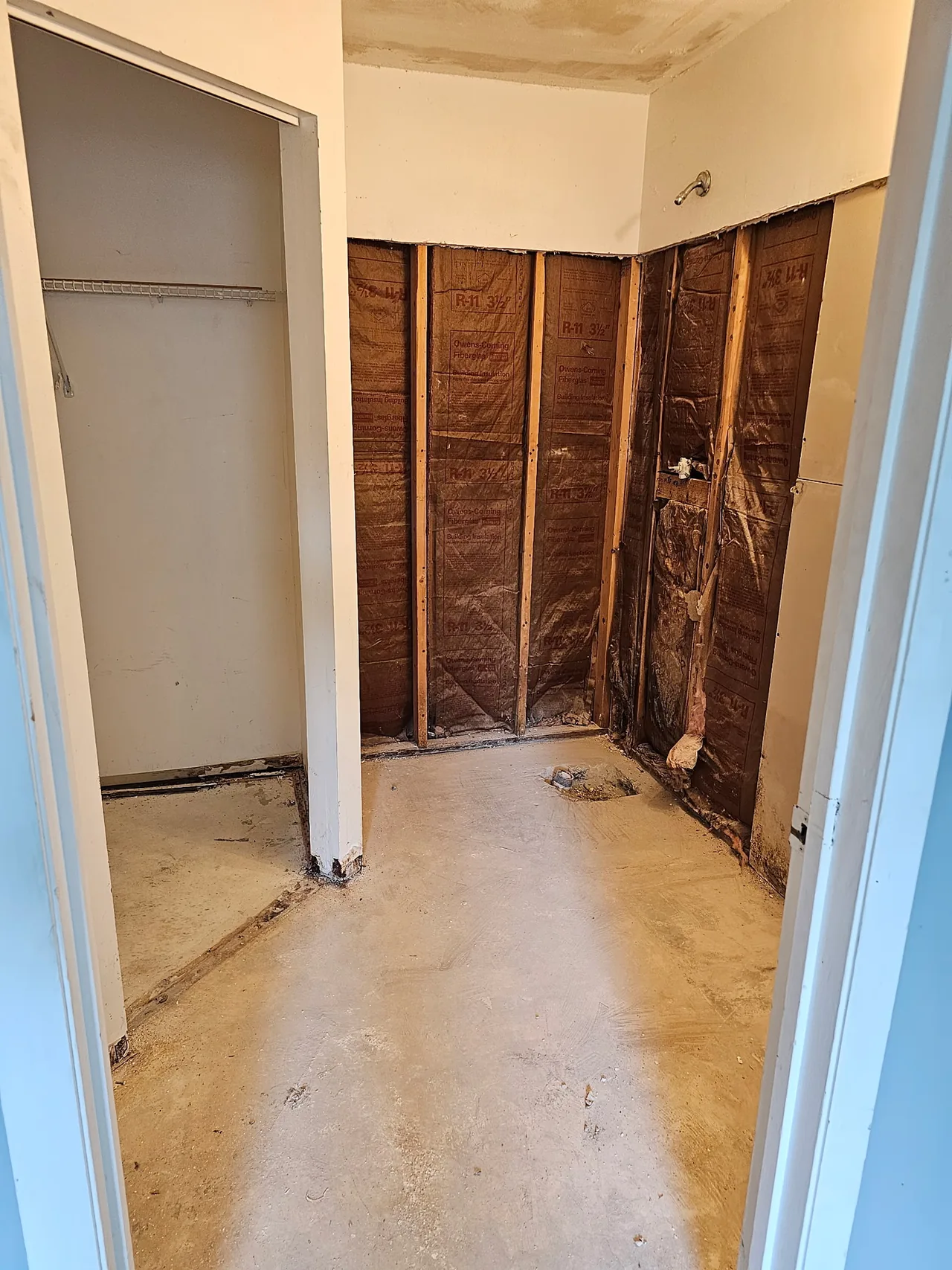 The old shower area stripped to the studs, insulation showing