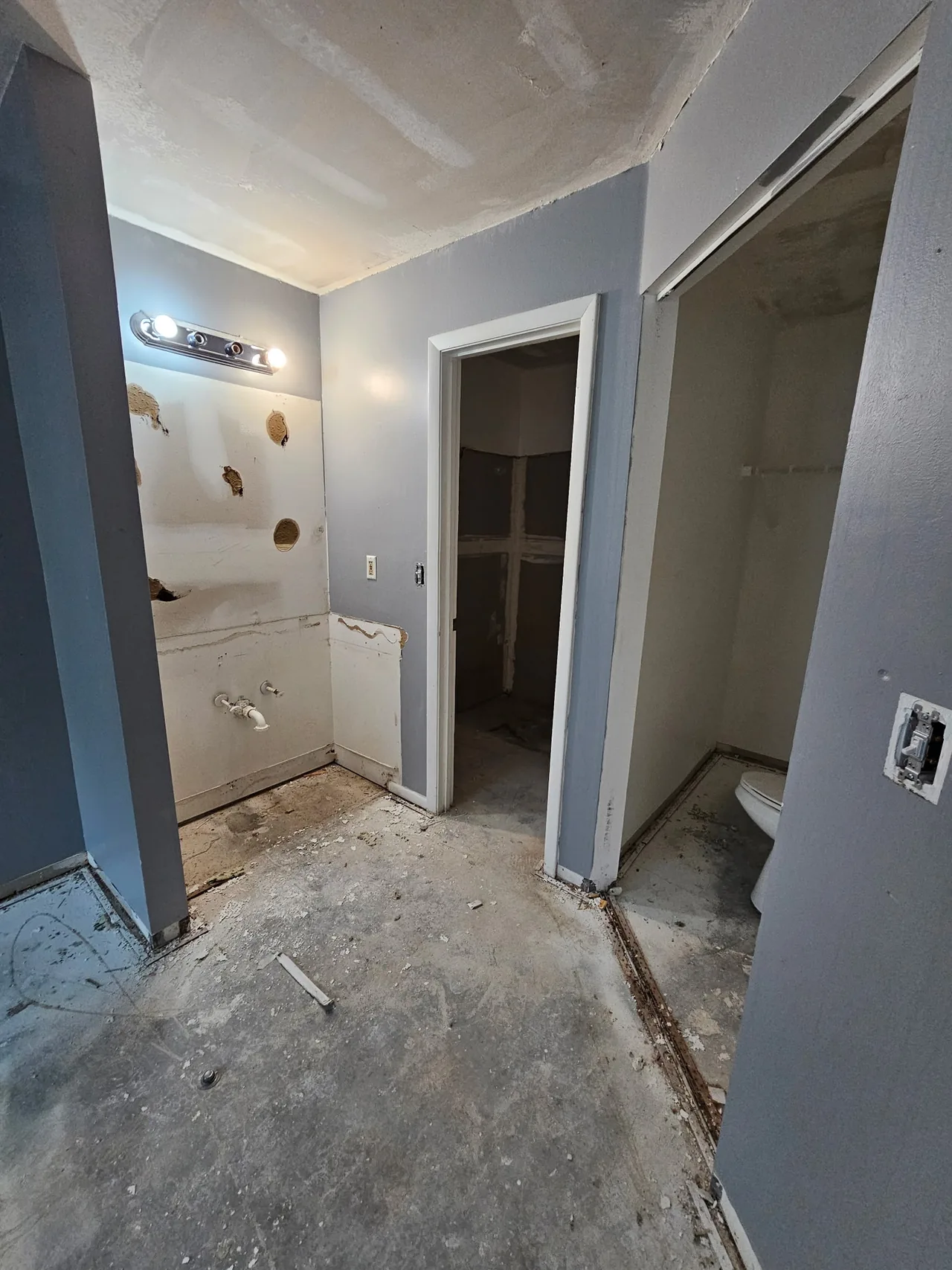 Before: the vanity wall opened up with patches and exposed plumbing