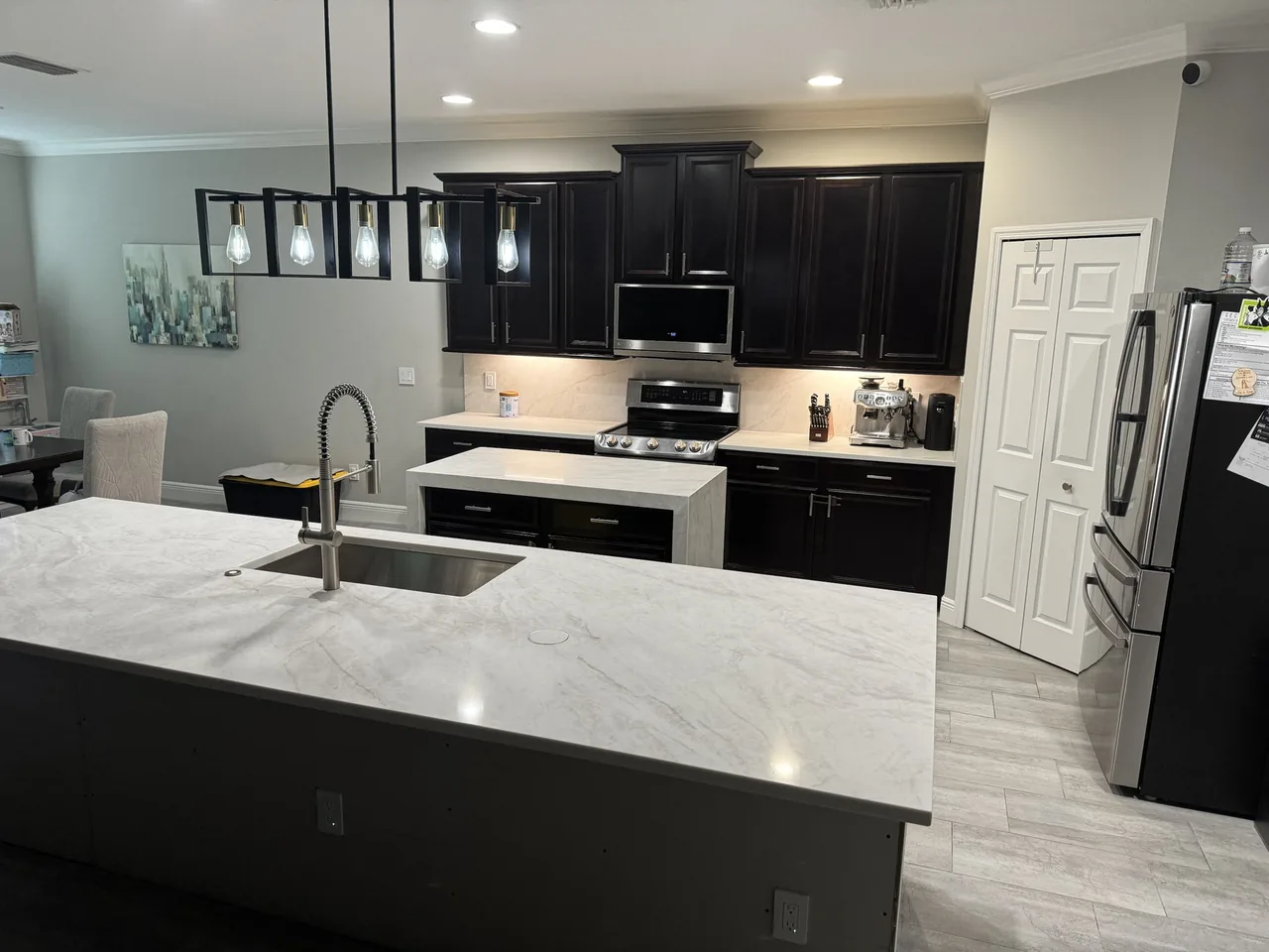 After: the same range wall with a slab backsplash, new stone counters and the long island in front