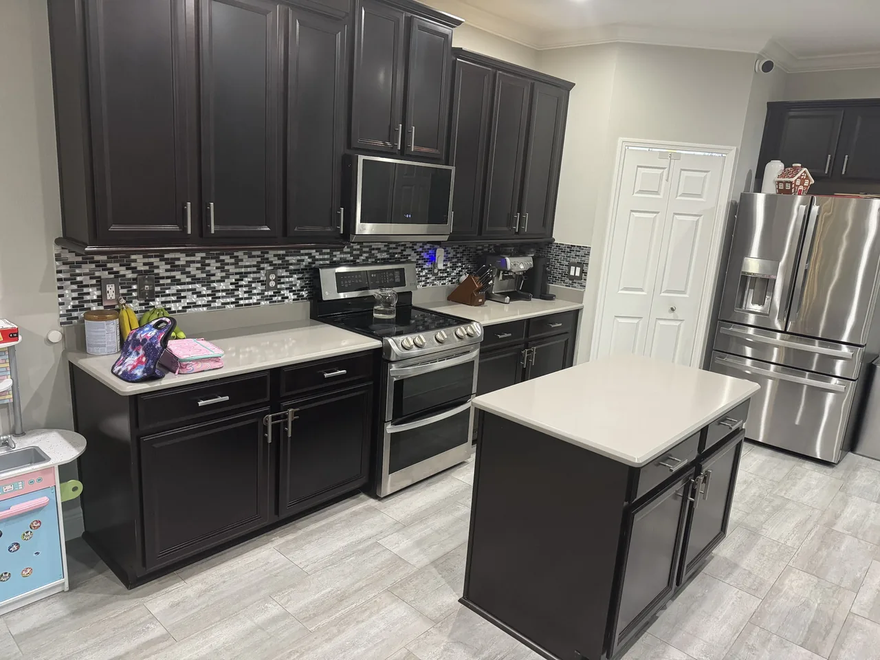 Before: the range wall with its glass mosaic backsplash and light counters