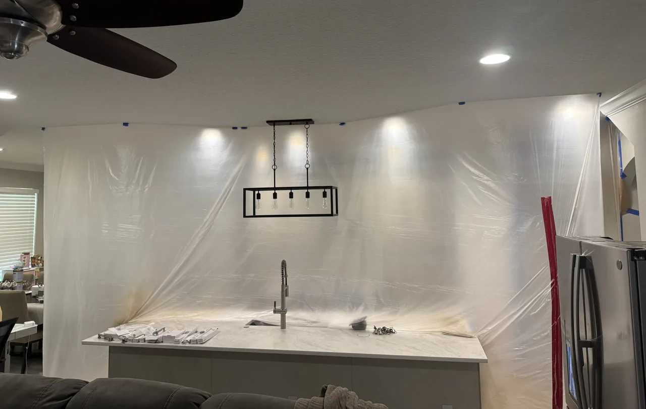 The kitchen sealed off from the living room with a wall of plastic sheeting during spraying