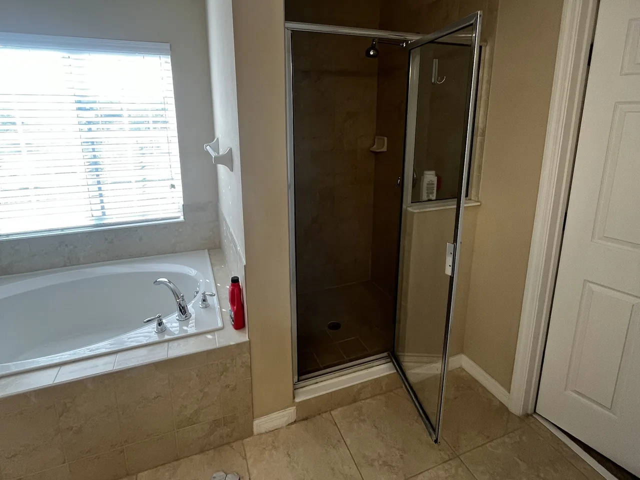 Before: the original beige tub deck and a small framed-glass shower