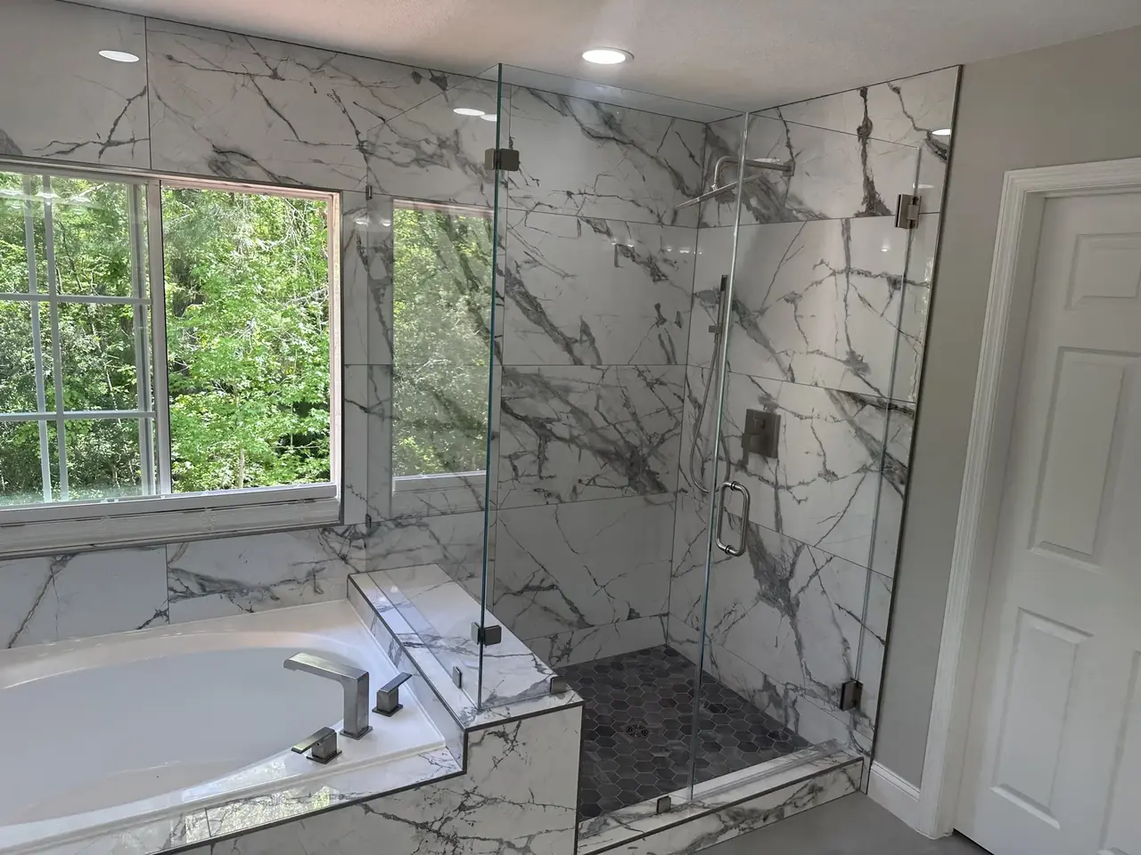 Baño principal terminado con porcelanato tipo mármol y vidrio sin marco