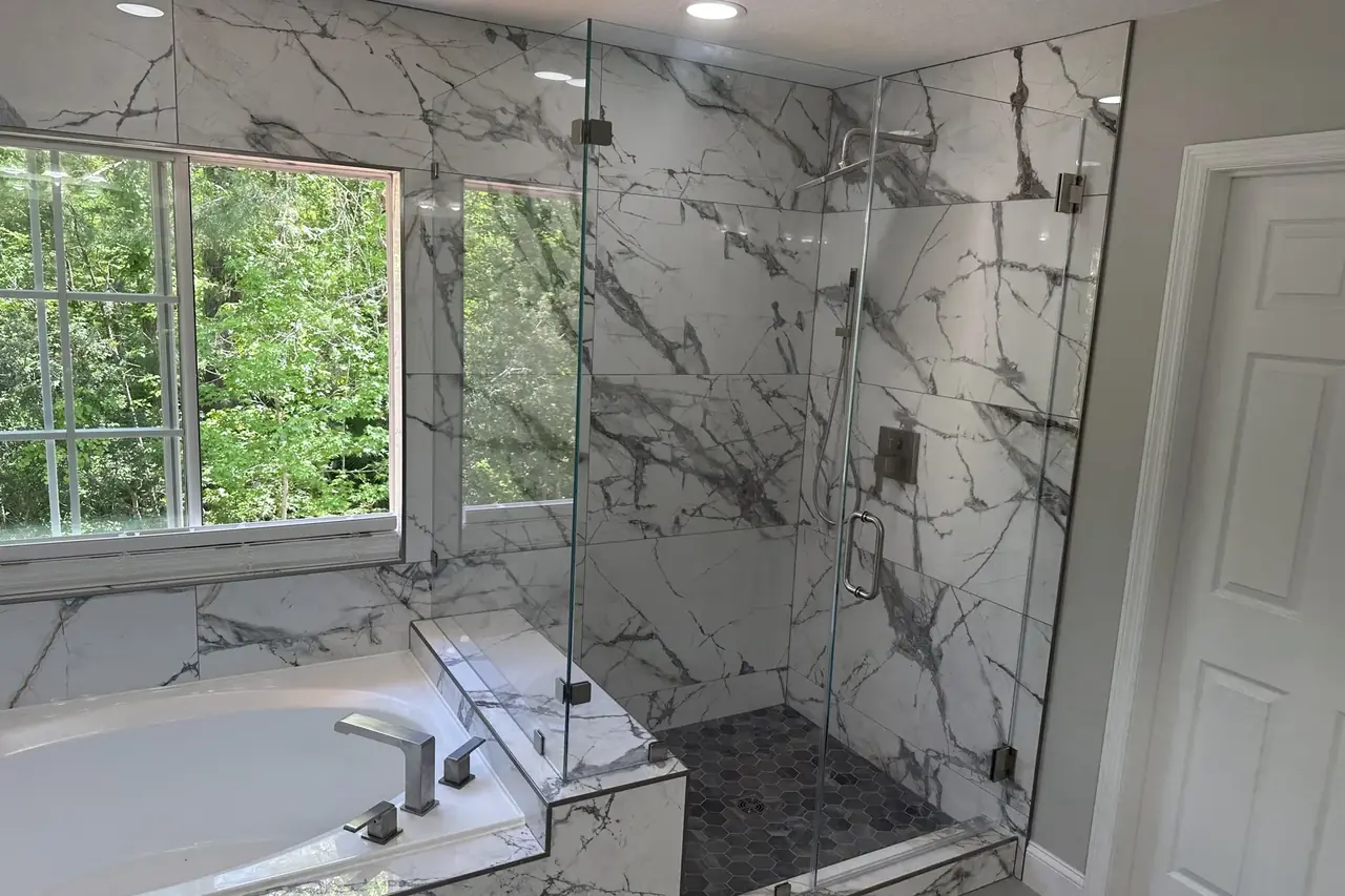 Finished primary bath in Sanford with marble-look porcelain and frameless glass