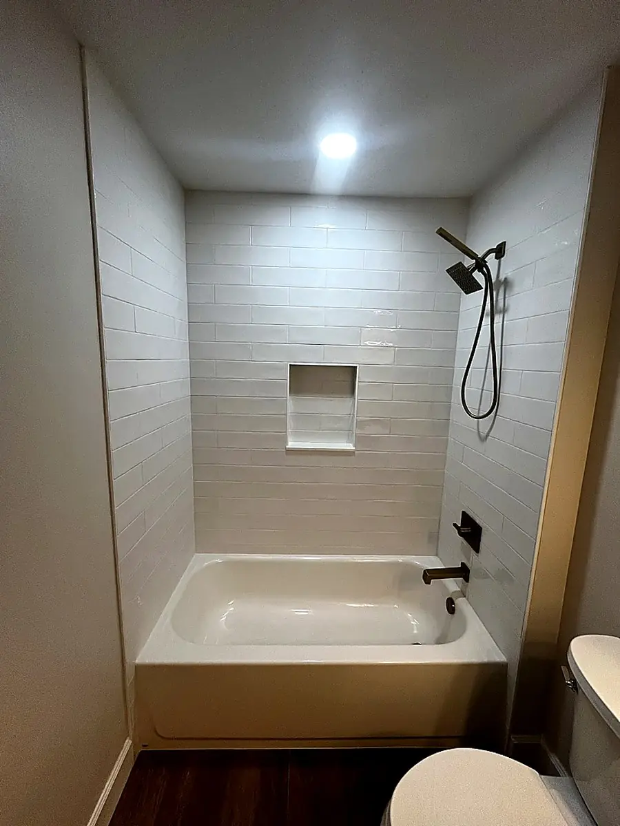 White subway tile tub surround with a recessed niche and matte black fixtures